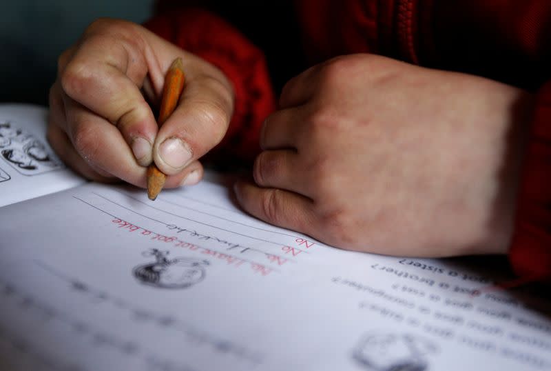 FILE PHOTO: Nine-year-old Bacho Tsiklauri writes in a school book during a lesson, at a school in the village of Makarta, north of Tbilisi