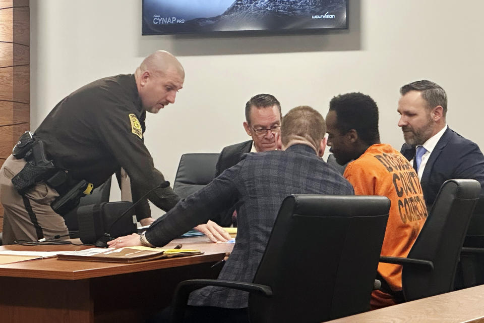 A Washington County Sheriff's deputy gives Kierre Williams and his attorneys some paperwork after a hearing Wednesday morning, Jan. 3, 2024, in Blair, Neb. Williams is charged with fatally stabbing a small-town priest during a Dec. 10, 2023, break in at the home where the priest lived next to his church in Fort Calhoun, Neb. (AP Photo/Josh Funk)