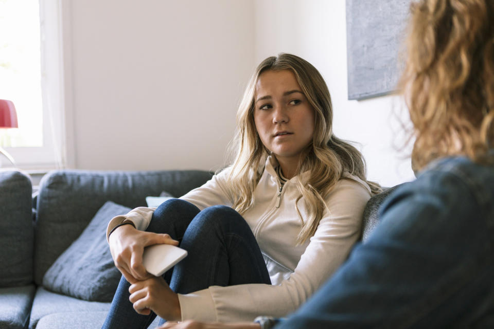 a teen on the couch talking to their mom