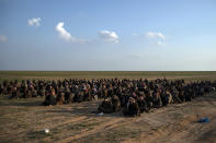 Men wait to be screened after being evacuated out of the last territory held by Islamic State militants, near Baghouz, eastern Syria, Friday, Feb. 22, 2019. (AP Photo/Felipe Dana)