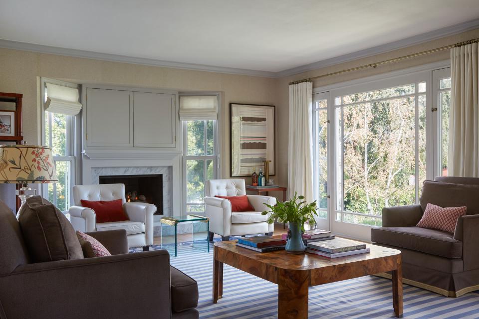 As a major gathering place in the home, the living room was designed for comfort and conversation. For example, a pair of cream leather Warren chairs by Martin & Brockett face the room (not the fireplace), the TV is hidden behind doors, and a burl wood coffee table gives guests plenty of room to place their drinks and plates. A woven Phillip Jeffries wallpaper adds to the warm vibe.