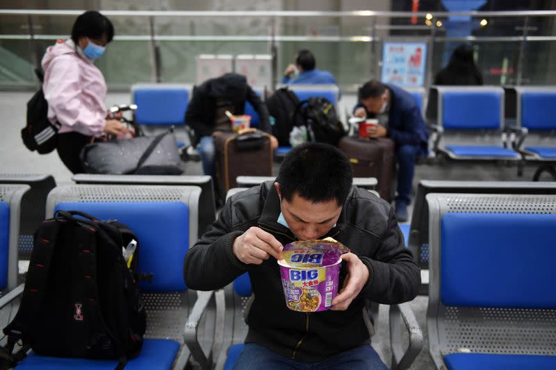 Travellers eat instant noodles at Wuchang Railway Station in Wuhan