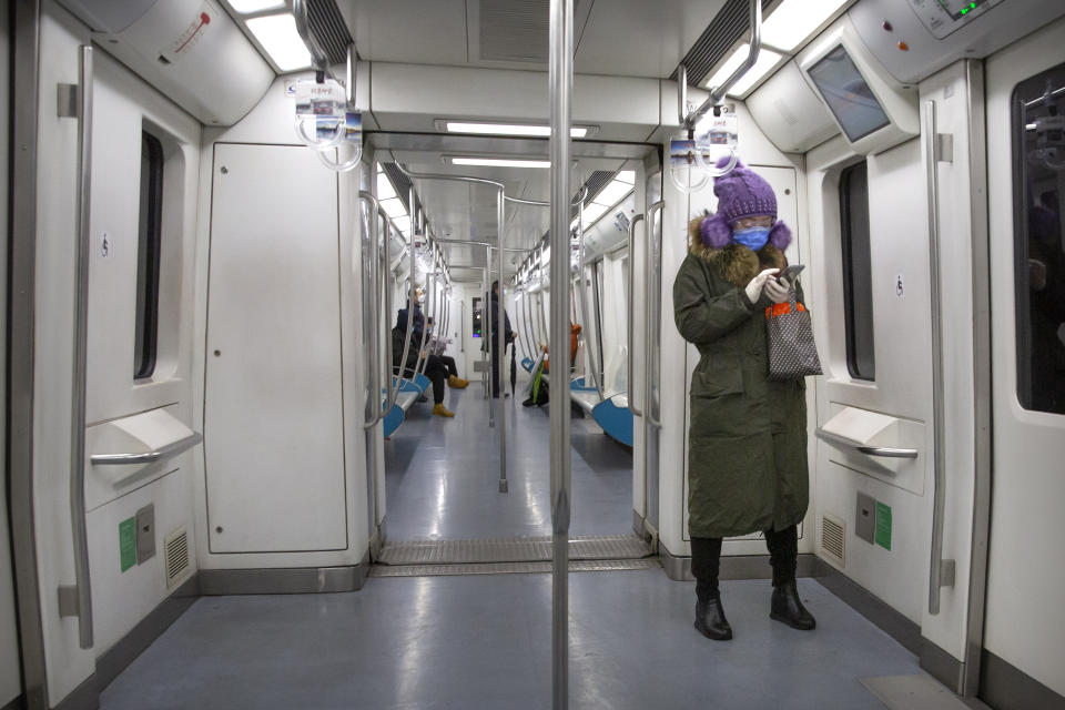 A woman wears safety goggles, a face mask, and rubber gloves as she rides a nearly empty subway train in Beijing, Friday, Feb. 14, 2020. China on Friday reported another sharp rise in the number of people infected with a new virus, as the death toll neared 1,400. (AP Photo/Mark Schiefelbein)