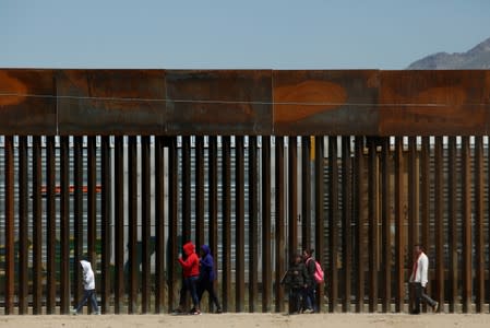 Migrants walk along the border fence after crossing illegally into El Paso, Texas, U.S., to request asylum, as seen from Ciudad Juarez