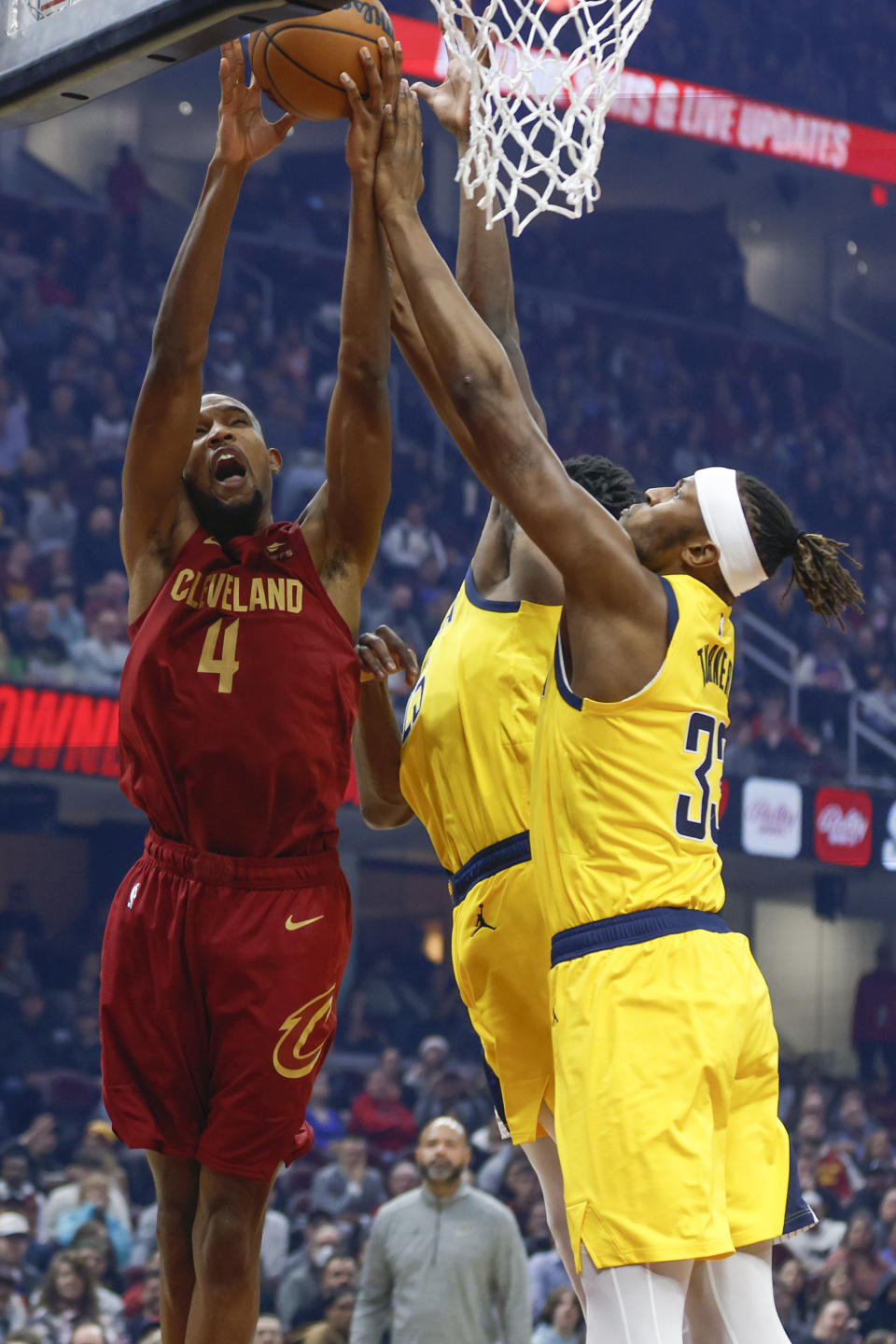 Cleveland Cavaliers forward Evan Mobley (4) shoots against Indiana Pacers center Myles Turner (33) and forward Jalen Smith during the first half of an NBA basketball game, Friday, Dec. 16, 2022, in Cleveland. (AP Photo/Ron Schwane)