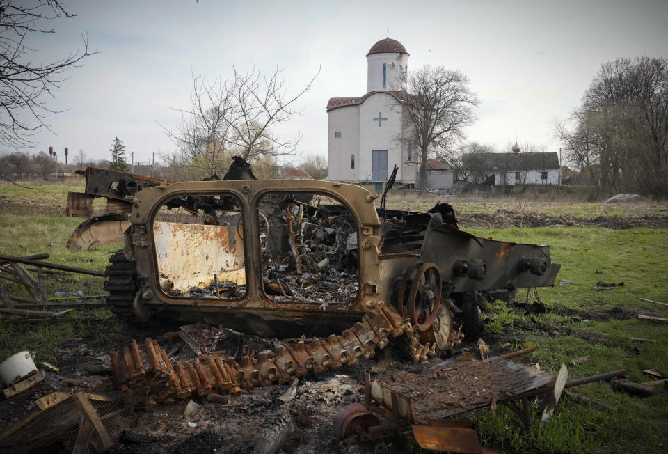 FILE - Fragments of a destroyed Russian military vehicle lie against the background of an Orthodox church in the village of Lypivka close to Kyiv, Ukraine, on April 11, 2022. Lypivka was occupied by the Russian troops at the beginning of the Russia-Ukraine war and freed recently by the Ukrainian army. Many Americans continue to question whether President Joe Biden is showing enough strength in response to Russia’s war against Ukraine, even as most approve of steps the U.S. is already taking and few want U.S. troops to get involved in the conflict. (AP Photo/Efrem Lukatsky, File)