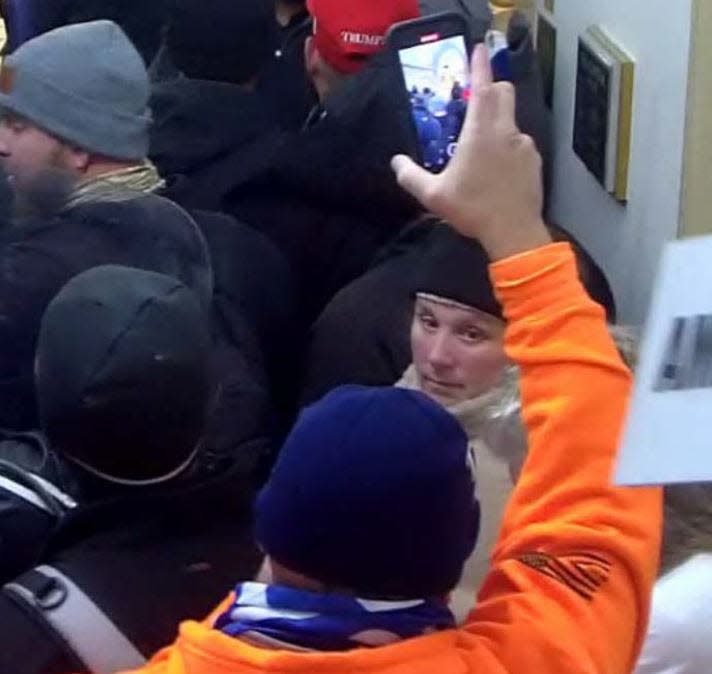 A close-up screengrab of a video showing Lori Ann Vinson and her husband, Thomas Roy Vinson, in the U.S. Capitol Rotunda on the 2nd floor during the Jan. 6 riots. Thomas is wearing an orange shirt and Lori a black hat.