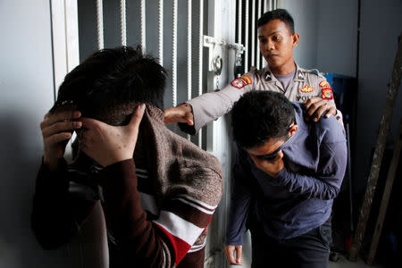 Two Indonesian men, who were later sentenced to 85 lashes of the cane for having sex together, are escorted by police into an Islamic court in Banda Aceh, Aceh province, Indonesia May 17, 2017. REUTERS/Junaidi Hanafiah