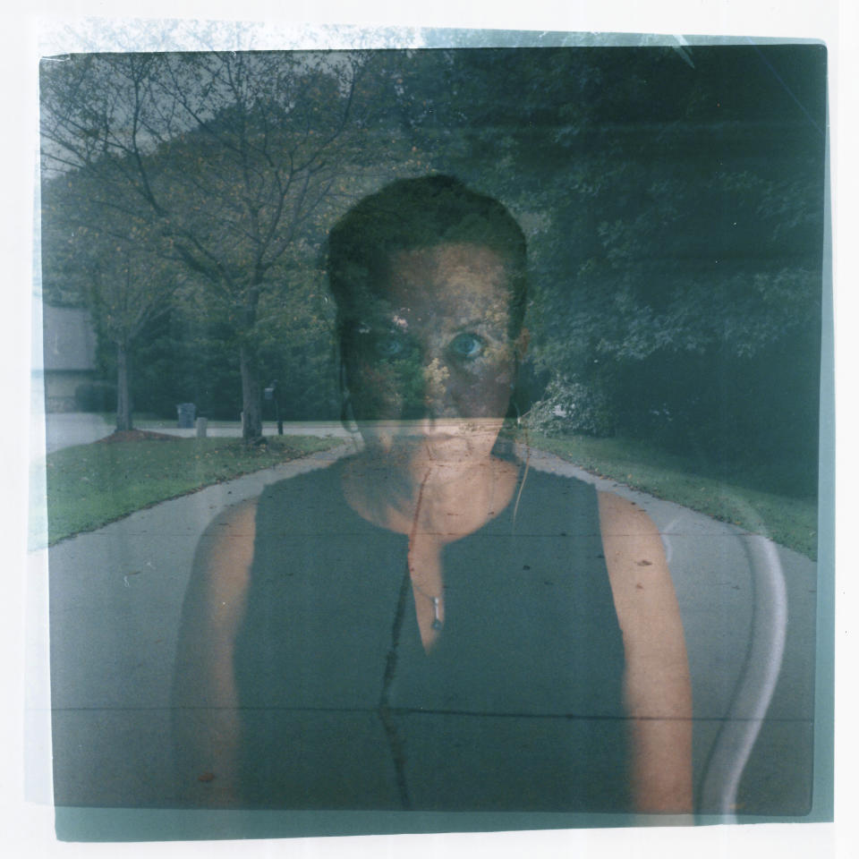 In this double exposure darkroom print made from two film negatives, a portrait of Janet Paulsen is layered with a photo of the driveway where her estranged husband shot her six times in 2015, before killing himself at the home where she still lives in Acworth, Ga., Tuesday, Aug. 8, 2023. As Paulsen prepared to leave her husband, who had become increasingly unstable over their 15-year marriage, she snuck down to his gun safes one night while he slept to try to change the combination locks. "When I went to get my protection order, I brought pictures of all of those firearms with me." When he violated that protection order, a court ordered deputies to confiscate his guns who removed about 70 firearms from their home. The deputies, though, left a handgun in a pickup truck parked in the driveway, unsure if the order covered his vehicle. Five days later, Scott Bland ambushed Paulsen in the garage as she stopped home with groceries. He used the 9 mm semiautomatic pistol to shoot her six times, as she tried to flee, before killing himself. "It took me five years to get up the courage to divorce him, because I knew I would pay a price. And you know what happened when I did? He shot me," said Paulsen, 53, a former property manager and endurance athlete who was left partially paralyzed in the shooting. Her care has since cost about $2.5 million, much of it born by society at large through health insurance payments. "Every step of the way it seemed like his rights were more important … than mine and my children's," she said, her normally stoic voice breaking. (AP Photo/David Goldman)