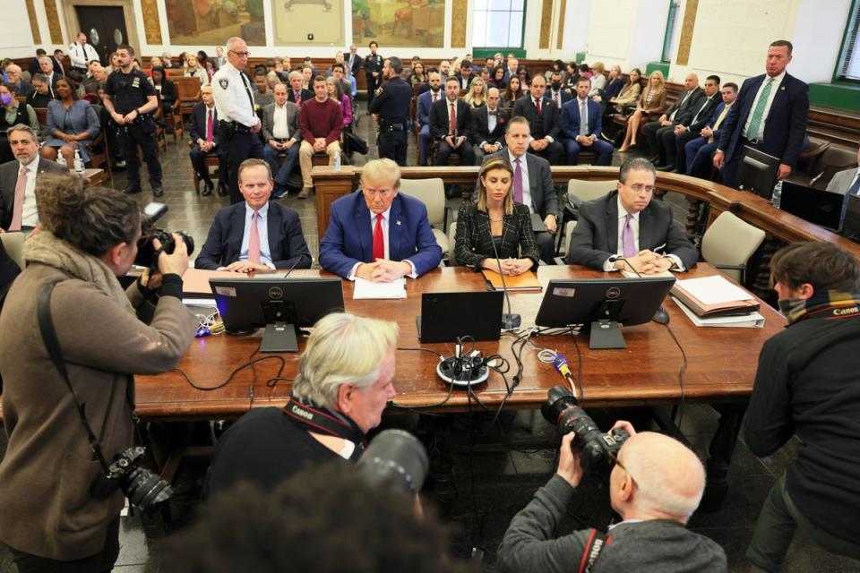 Photographers surround Donald Trump and his attorneys before closing arguments in a civil fraud case in New York on 11 January. (AP)