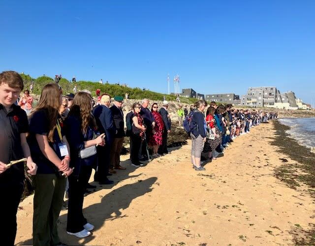 High school students, teachers and staff from the Anglophone North School District attened a ceremony on the beach at St. Aubin sur Mer on Thursday morning, where 270 wooden crosses were left in the sand.  (Submitted by Meredith Caissie - image credit)