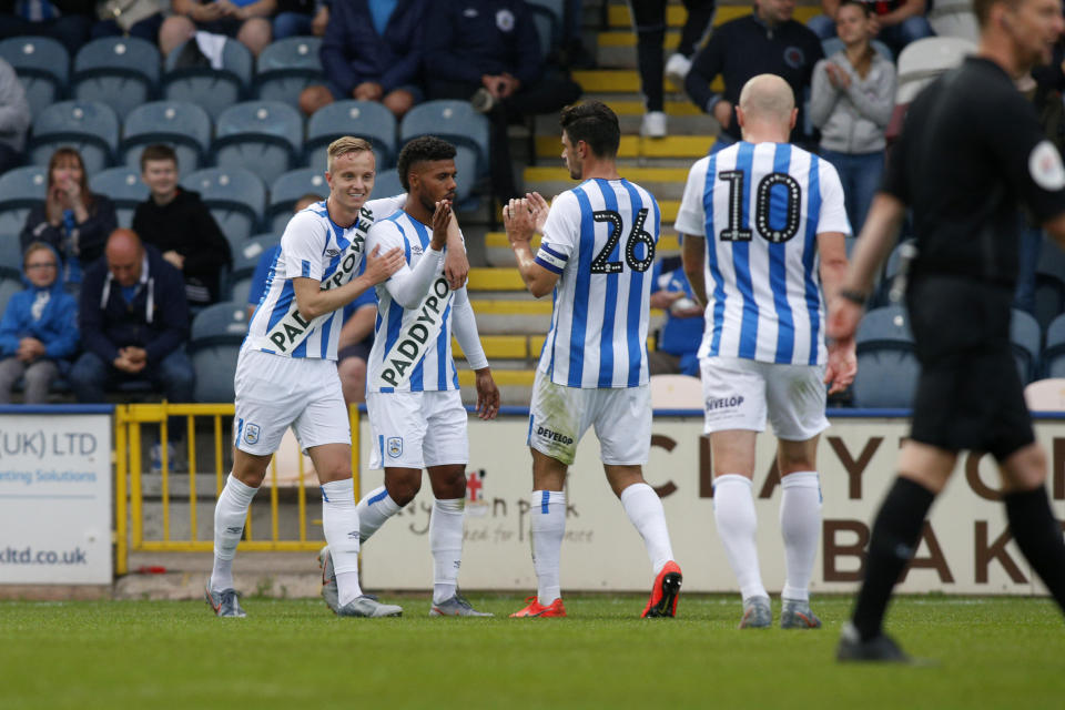 ROCHDALE, ENGLAND - JULY 17: Elias Kachunga scores and is congratulated by Huddersfield team mates Florent Hadergjonaj, Christopher Schindler, and Aaron Mooy during the game between Rochdale and Huddersfield Town at the Crown Oil Arena on July 17, 2019 in Rochdale, England. (Photo by John Early/Getty Images)