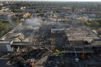 Ukrainian State Emergency Service firefighters work to take away debris at a shopping center burned after a rocket attack in Kremenchuk, Ukraine, Tuesday, June 28, 2022. (AP Photo/Efrem Lukatsky)