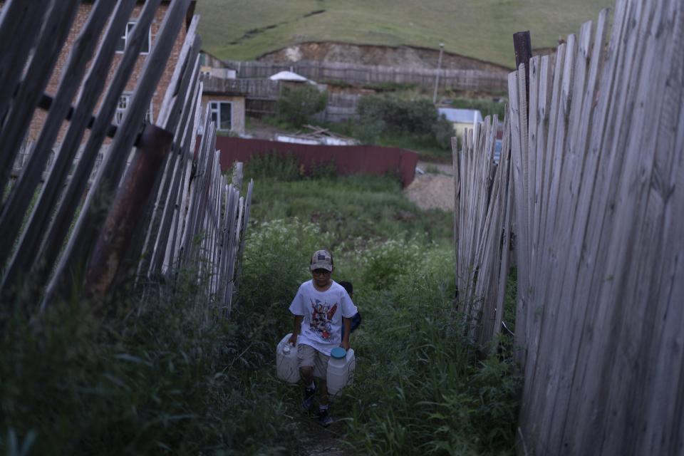 Twelve-year-old Gerelt-Od Kherlen walks the route to a water kiosk near his home in a Ger district on the outskirts of Ulaanbaatar, Mongolia, Tuesday, July 2, 2024. Growing up in a Ger district without proper running water, Gerelt-Od fetched water from a nearby kiosk every day for his family. Carrying water and playing ball with his siblings and other children made him strong and resilient. (AP Photo/Ng Han Guan)