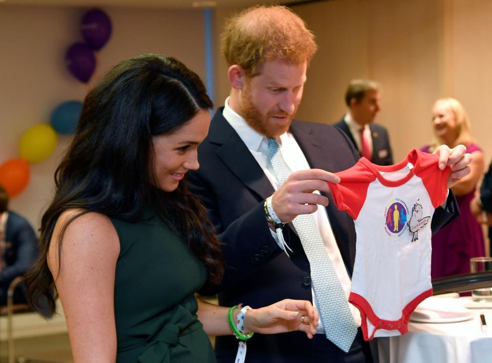 Prince Harry and Duchess Meghan of Sussex look at a gift for baby Archie at the annual WellChild Awards in London on Oct. 15, 2019.