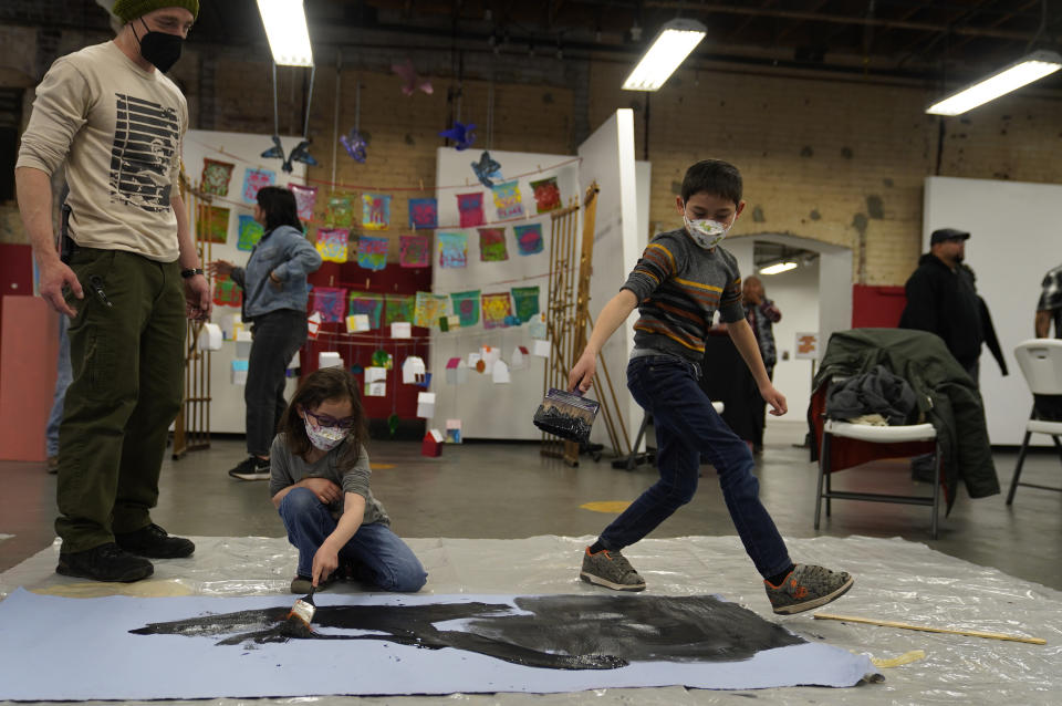 Volunteers join members of the Apache Stronghold group who traveled from Arizona paint protest banners at Self Help Graphics & Art in the Los Angeles neighborhood of Boyle Heights on Monday, March 20, 2023. The Apache group battling a foreign mining firm that wants to build one of the largest copper mines in the United States on what tribal members say is sacred land will get a new chance to make its point Tuesday when a full federal appeals court panel takes another look at the case. (AP Photo/Damian Dovarganes)