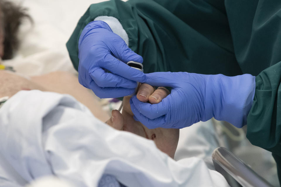 A nurse adjusts a patient's oximeter in the COVID-19 intensive care unit of the Tor Vergata Polyclinic Hospital in Rome, Sunday, Dec. 13, 2020. Italy is reclaiming a record that nobody wants: The most coronavirus deaths in Europe. Italy is still trying to figure out how to protect its vulnerable elderly. (AP Photo/Alessandra Tarantino)