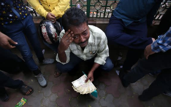 epa05632112 An Indian man, holding old Indian rupee bills, gestures as he waits in queue along with others to change old notes outside Reserve Bank of India, in New Delhi, India, 15 November 2016. Indian Prime Minister Narendra Modi announced the elimination of the 500 and 1,000 rupee bills ($7.37 and 14.73, respectively), hours before the measure took effect at midnight 08 November, for the purpose of fighting against 'black money' (hidden assets) and corruption in the country. The decision sparked some protests, while storekeepers complained about dwindling sales because many citizens lack the cash to buy the most basic products, as lines get longer at ATMs and banks.  EPA/RAJAT GUPTA