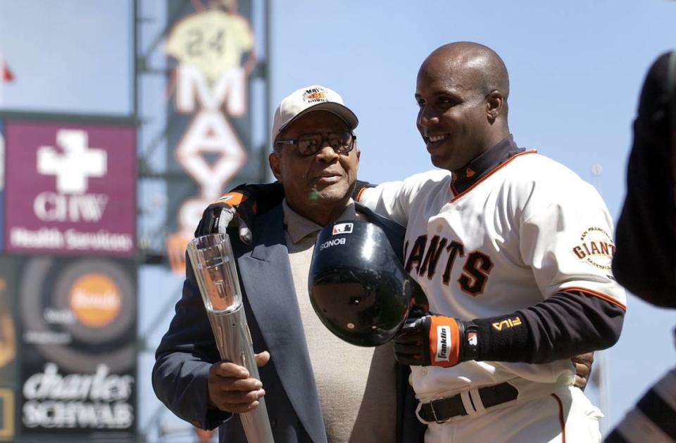 The San Francisco Giants’ Barry Bonds is given a torch by his godfather Willie Mays after hitting his 660th home run, tying Mays’s record, at SBC Park in San Francisco on April 12, 2004.