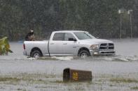 A man rides on the back of a pick up truck through flood water as it rains in Sorrento, Louisiana. REUTERS/Jonathan Bachman