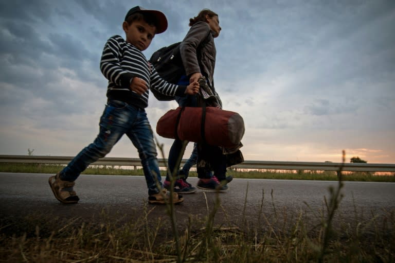 A migrant holds her son's hand as they walk towards the border with Hungary, near the northern Serbian town of Kanjiza, on June 25, 2015