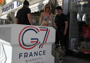 A woman with her family walks past police officers inside the restricted area ahead of the G-7 summit in Biarritz, France Friday, Aug. 23, 2019. U.S. President Donald Trump will join host French President Emmanuel Macron and the leaders of Britain, Germany, Japan, Canada and Italy for the annual G-7 summit in the elegant resort town of Biarritz. (AP Photo/Peter Dejong)