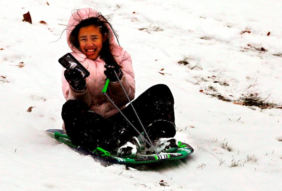 Erika Ardiente uses her cell phone to capture her sled ride down the snow covered hill at Carmichael Middle School in Richland after the school district canceled classes because of the winter weather.