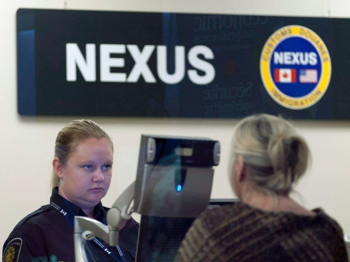 A Canada Border Services Agency officer speaks with a traveller at the Nexus office at the airport in Ottawa on May 8, 2012. (Adrian Wyld/The Canadian Press - image credit)