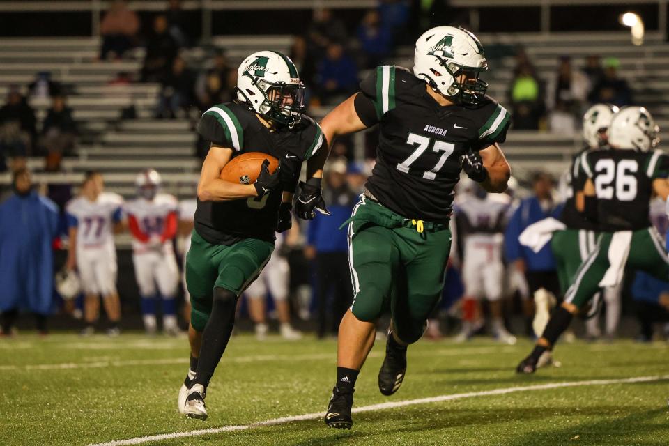 Aurora’s Jack Cardaman runs behind offensive lineman Kevin Paul during Friday night’s Division III playoff game against Ravenna High School.