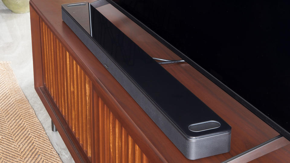  Bose Smart Ultra Soundbar in front of a TV on a wooden surface. 