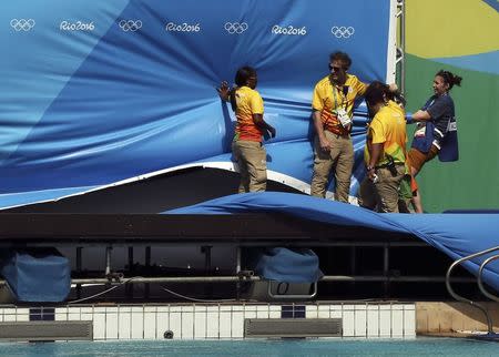 Rio Olympics - Diving - Olympic Park - Rio de Janeiro, Brazil - 07/08/2016. Workers hold onto banners being blown by high winds at the Olympic diving venue. REUTERS/Stefan Wermuth