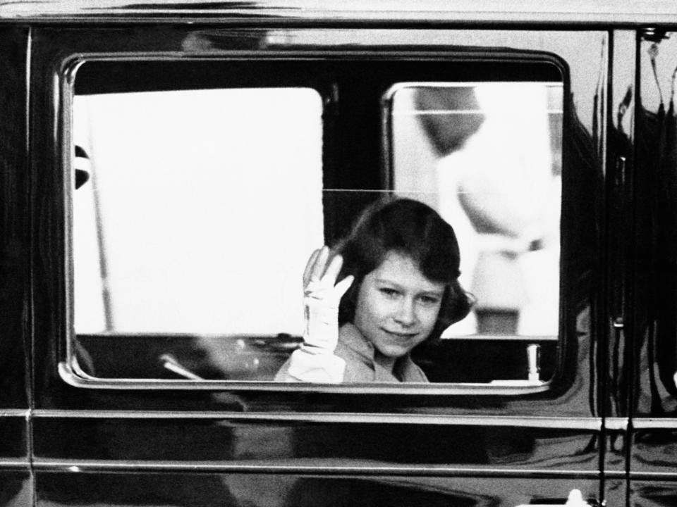 A young Queen Elizabeth waves from a car