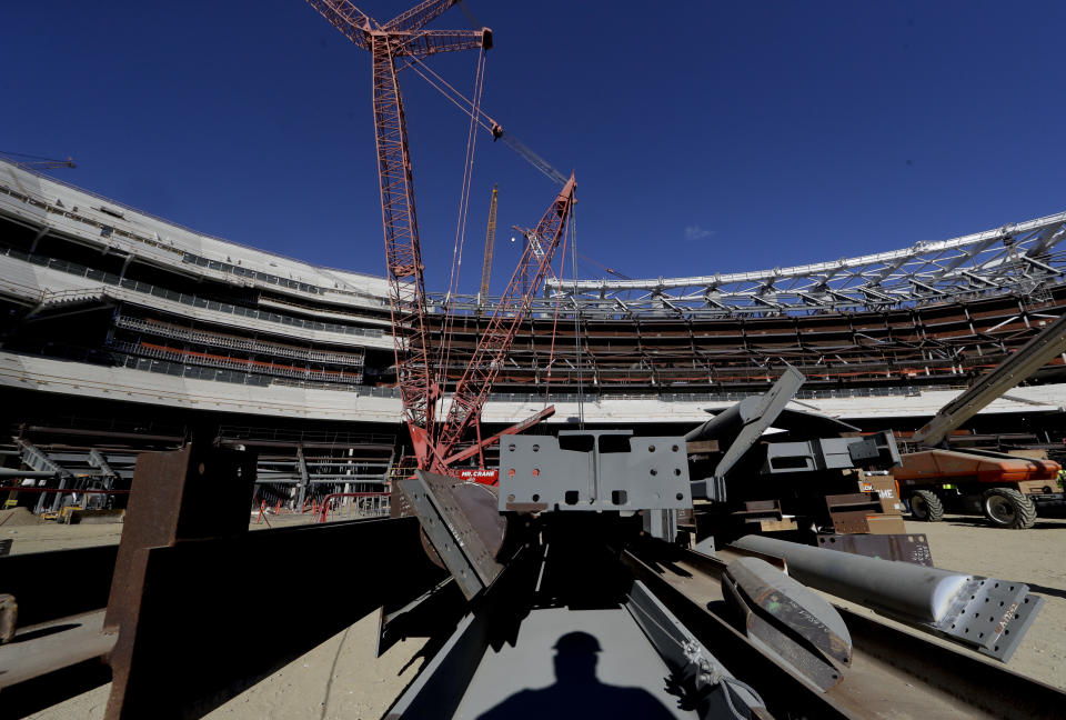 FILE - In this Tuesday, Sept. 18, 2018, file photo, a large crane looms over LA Stadium in Inglewood, Calif. The Los Angeles Chargers have announced that season-ticket prices for non-premium seats in the new LA Stadium at Hollywood Park will range from $50 to $150 per game. The new stadium in Inglewood will have a capacity of 70,240 with 260 suites and 13,000 premium seats when it opens for the 2020 season. (AP Photo/Chris Carlson, File)