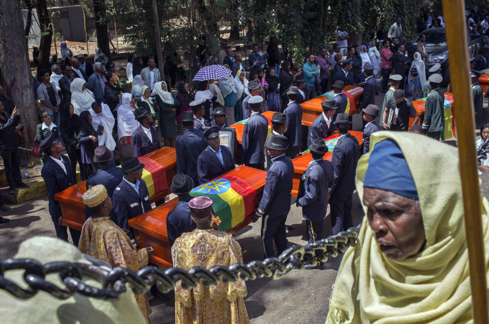 Relatives grieve next to empty caskets draped with the national flag at a mass funeral at the Holy Trinity Cathedral in Addis Ababa, Ethiopia Sunday, March 17, 2019. Thousands of Ethiopians have turned out to a mass funeral ceremony in the capital one week after the Ethiopian Airlines plane crash. Officials have begun delivering bags of earth to family members of the 157 victims of the crash instead of the remains of their loved ones because the identification process is going to take such a long time. (AP Photo/Mulugeta Ayene)