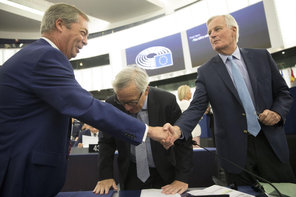 Brexit Party leader Nigel Farage, left, shakes hands with European Union chief Brexit negotiator Michel Barnier while European Commission President Jean-Claude Juncker leans forward Wednesday, Sept. 18, 2019 in Strasbourg. Members of the European Parliament discuss the current state of play of the UK's withdrawal from the EU. (AP Photo/Jean-Francois Badias)