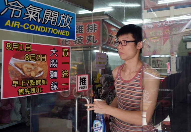 Carlos Cheung, 28, a Hong Kong emigrant to Taiwan, cleans windows of a restaurant where he runs his noodle stall, in central Taichung