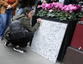 A person signs a message board at a makeshift memorial for Matthew Perry outside the building shown in exterior shots of the television show "Friends" on Monday, Oct. 30, 2023, in New York. Perry, who played Chandler Bing on NBC's "Friends" for 10 seasons, was found dead at his Los Angeles home on Saturday. He was 54. (Photo by Charles Sykes/Invision/AP)
