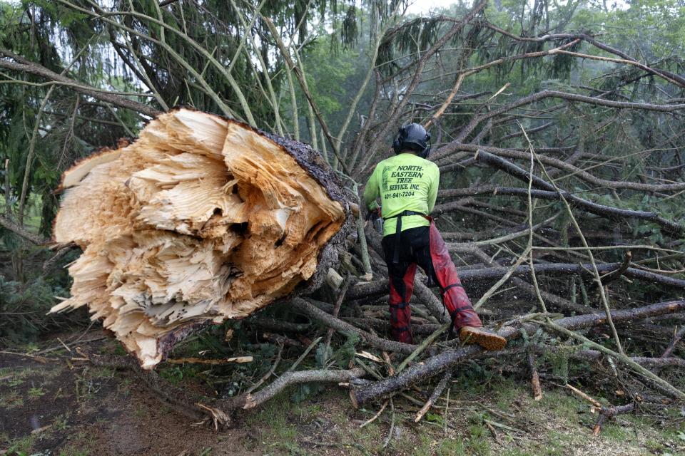 A worker clears a downed tree in Highland Memorial Park Cemetery, Friday, Aug. 18, 2023, in Johnston, R.I., after severe weather swept through the area. (AP Photo/Michael Dwyer)