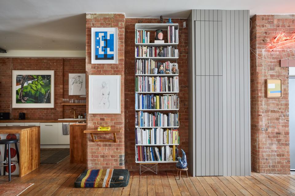 Tovey says he never feels guilty about buying books or music, and, as a consequence, he has several bookshelves, loaded with art books, around the apartment. Here a Vitsoe shelf system sits alongside a bespoke tongue-and-groove cabinet, made to Tovey’s specifications and concealing electrical and pipe work. Above the wall shelf are works by Leon Polk Smith (top) and George Condo (below). The sculpture on the floor by the bookcase is by Sebastian Stöhrer. Works on the bookshelves include a Bart Simpson figure by Joyce Pensato and ceramic cartoon figures by Magdalena Suarez Frimkess.
