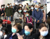 Passengers wearing protective face masks enter the departure hall of a high speed train station in Hong Kong, Friday, Jan. 24, 2020. China expanded its lockdown against the deadly new virus to an unprecedented 36 million people and rushed to build a prefabricated, 1,000-bed hospital for victims Friday as the outbreak cast a pall over Lunar New Year, the country's biggest, most festive holiday..(AP Photo/Achmad Ibrahim)