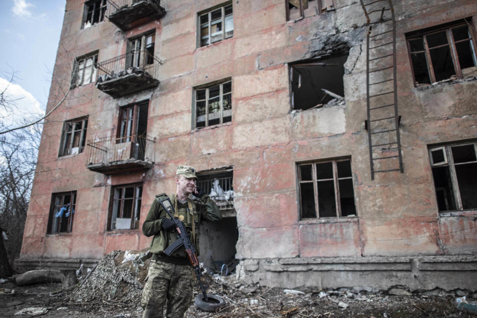 A Ukrainian solder speaks by phone in front of a destroyed house as he patrols in the village of Zolote 4, eastern Ukraine, Friday, March 29, 2019. Five years after a deadly separatist conflict in eastern Ukraine, the front line between government forces and Russia-backed separatists has become a de-facto border, cutting off a generation of first-time voters from Sunday's presidential election. (AP Photo/Evgeniy Maloletka)