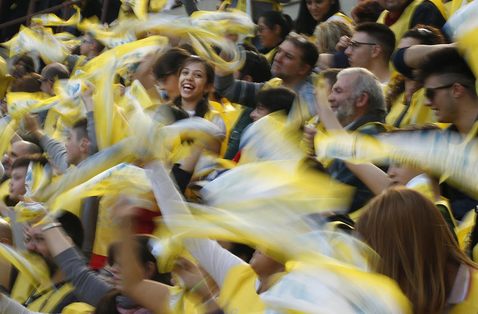 The faithful wave scarves as they await the arrival of Pope Francis