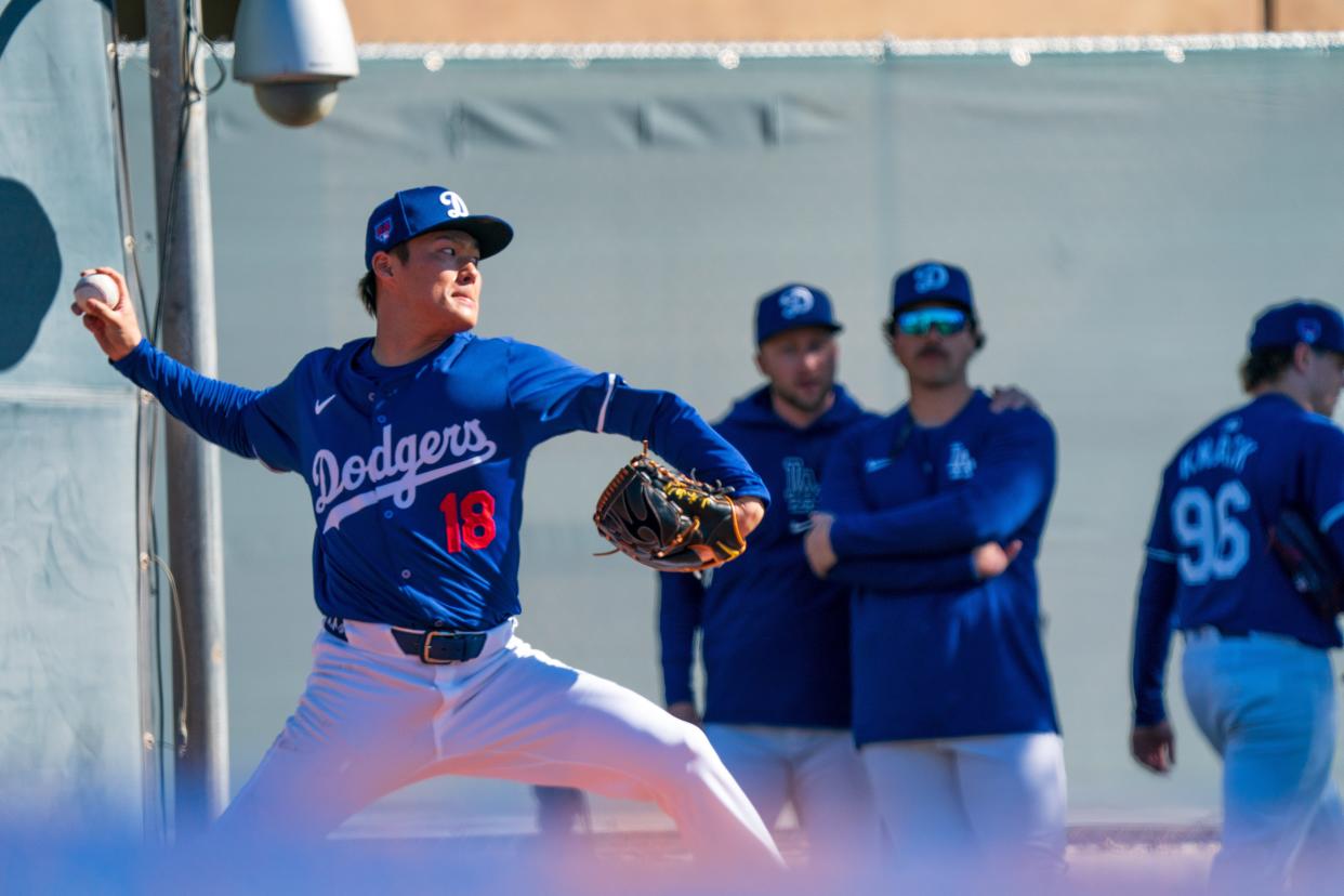 New Dodgers pitcher Yoshinobu Yamamoto throws as teammates look on at Camelback Ranch.