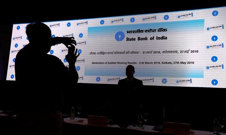 A man takes photo of his colleague with a mobile phone in front of a screen displaying State Bank of India (SBI) logo before the start of a news conference in Kolkata, India May 27, 2016. REUTERS/Rupak De Chowdhuri