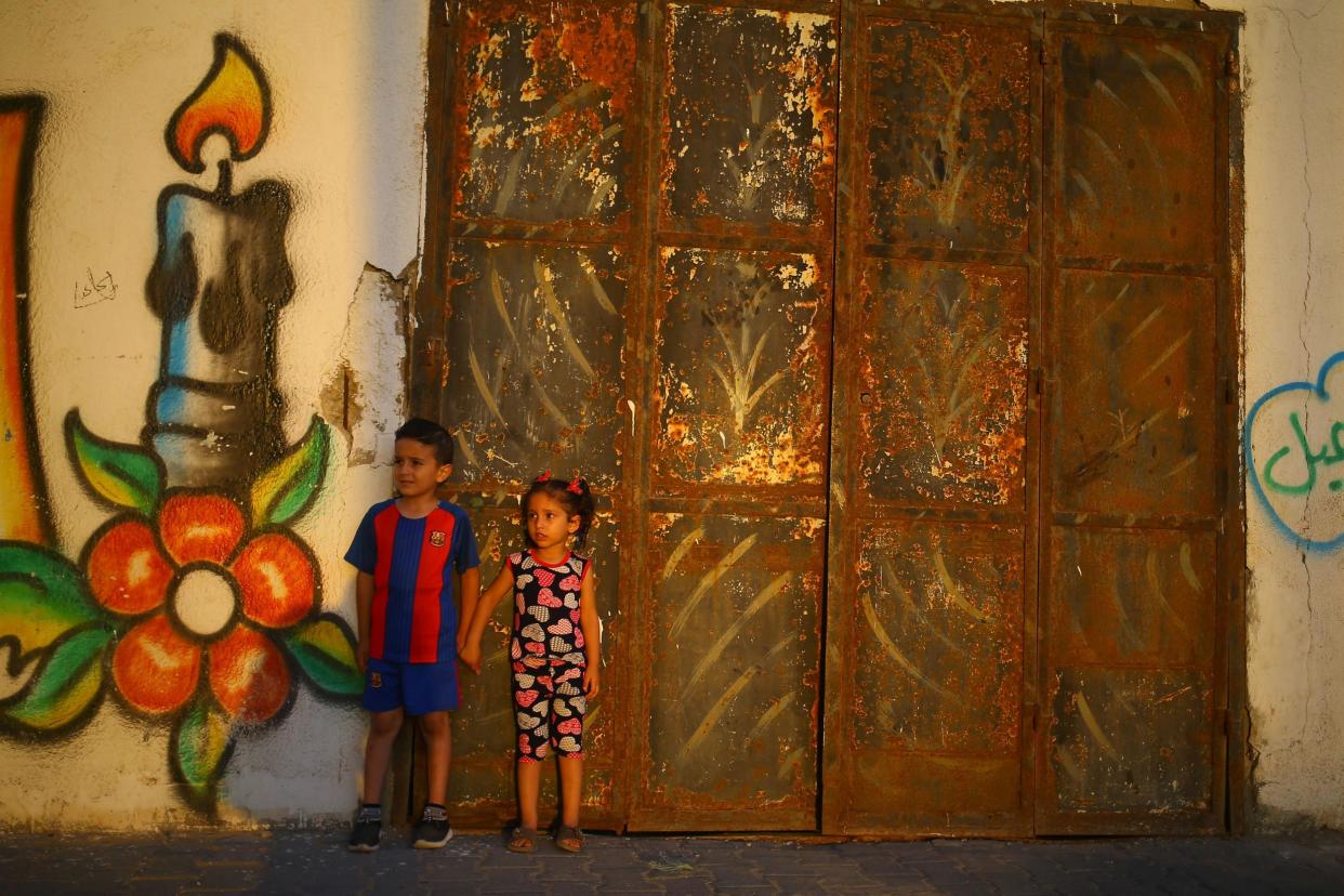 Palestinian children stand in front of a mural as the sun sets on 20 June 20 2017 in Gaza City: AFP/Getty Images