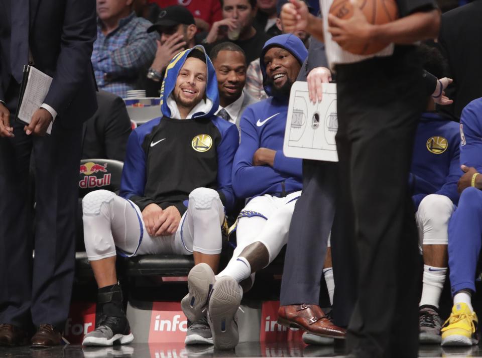 Golden State Warriors' Stephen Curry, left, and Kevin Durant smile during the first half of an NBA basketball game against the Brooklyn Nets, Sunday, Oct. 28, 2018, in New York. (AP Photo/Frank Franklin II)