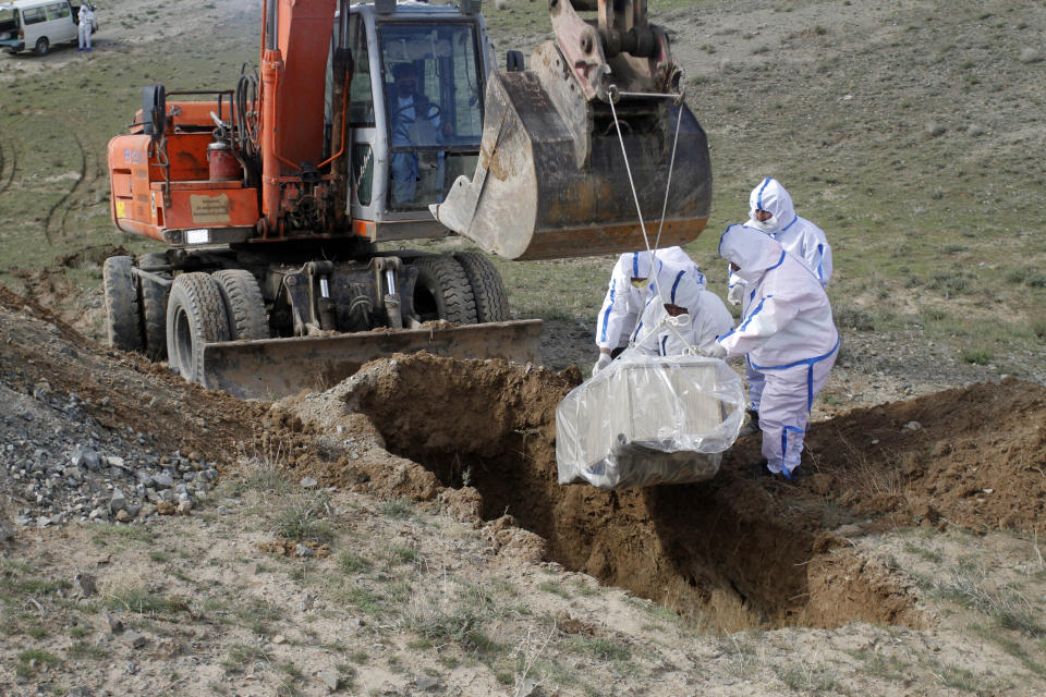 FILE - In this Friday, March 27, 2020 file photo, municipality workers bury the body of coronavirus victim on the outskirts of Herat province west of Kabul, Afghanistan. Some 200,000 Afghans and counting have returned from Iran to their home country after losing their jobs in the coronavirus pandemic or out of fear of getting infected. They are flowing across the border from a country that has one of the world's worst outbreak to an impoverished nation that is woefully unprepared to deal with the virus. (AP Photo/Hamed Sarfarazi, File)