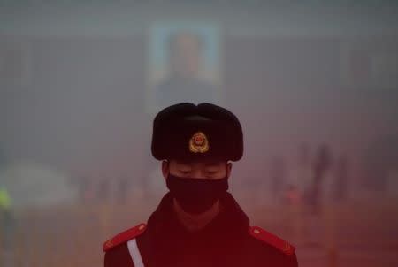A paramilitary police officer wearing a mask stands guard in front of a portrait of the late Chairman Mao Zedong during smog at Tiananmen Square after a red alert was issued for heavy air pollution in Beijing, China, December 20, 2016. REUTERS/Jason Lee