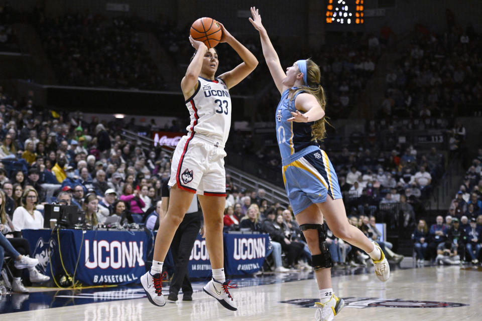 Connecticut's Caroline Ducharme (33) shoots over Marquette's Claire Kaifes (10) in the first half of an NCAA college basketball game, Saturday, Dec. 31, 2022, in Storrs, Conn. (AP Photo/Jessica Hill)