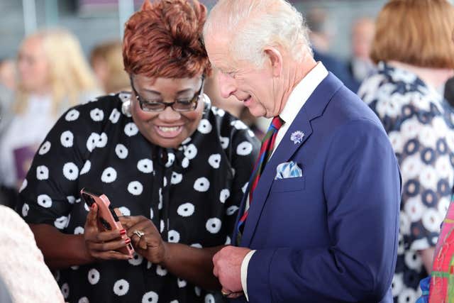 Charles looks at a member of the community's phone 